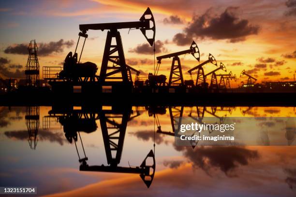 oil pumps and rig at sunset by the sea - exploração mineira imagens e fotografias de stock