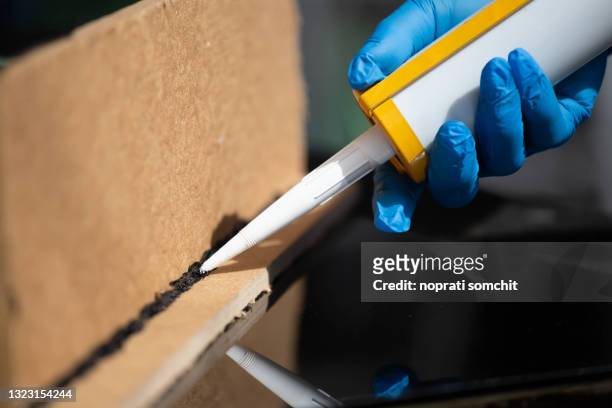 craftsmen are using silicone adhesives for general and industrial applications.  premium acetoxy silicone sealant - caulk stock pictures, royalty-free photos & images