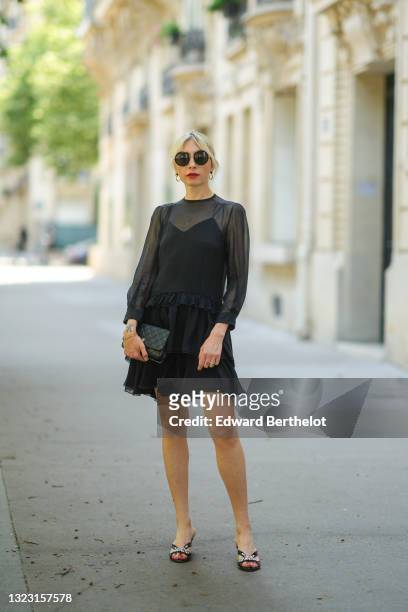 Emy Venturini wears black sunglasses from Linda Farrow & The Row, gold earrings, a Saint-Laurent YSL necklace, a black silk tank top, a black...