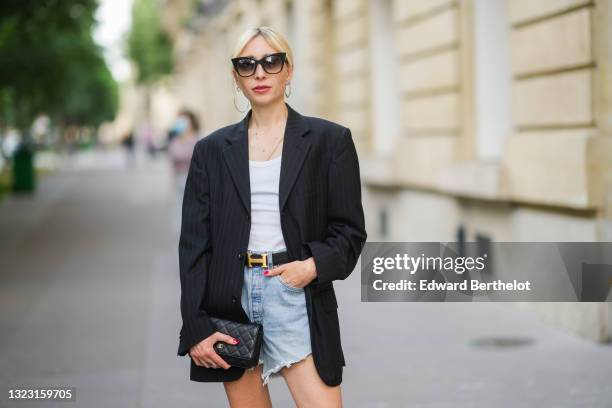 Emy Venturini wears black sunglasses from Dita, silver earrings, a gold chain necklace, white V-neck t-shirt from Intimissimi, a black with beige...