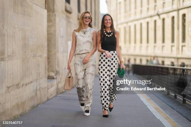 Natalia Verza wears brown sunglasses, a silver and black Prada earring, a beige and brown tie and dye Prada logo tank-crop-top, beige and brown tie...