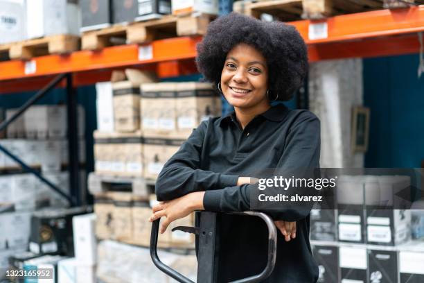 portrait d’une femme heureuse travaillant dans un entrepôt d’usine - magasinier photos et images de collection