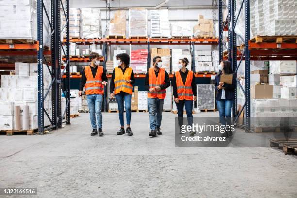 team of warehouse workers wearing face masks at work - vitale beroepen stockfoto's en -beelden