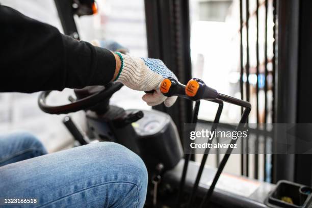 nahaufnahme eines arbeiters, der gabelstapler im lager fährt - forklift stock-fotos und bilder