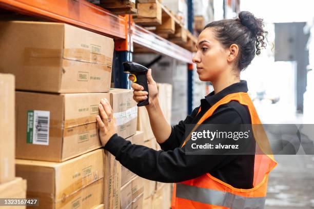 woman scanning boxes with bar code scanner in warehouse shelf - código-de-barras imagens e fotografias de stock
