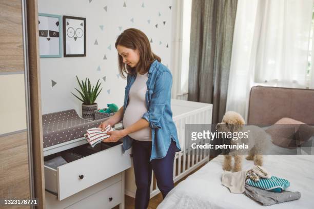 pregnant woman arranging clothes - geplooid stockfoto's en -beelden