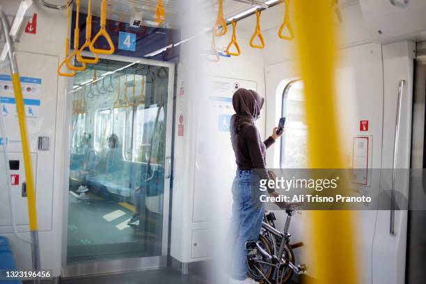 asian young hijab woman, inside train, with her bike - klapprad business stock-fotos und bilder