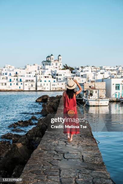 woman in red dress walking towards naoussa in paros, greece - paros greece stock pictures, royalty-free photos & images