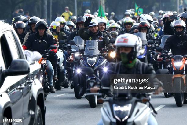 President of Brazil Jair Bolsonaro rides a motorcycle along with supporters during a motorcycle rally through the streets of Sao Paulo on June 12,...