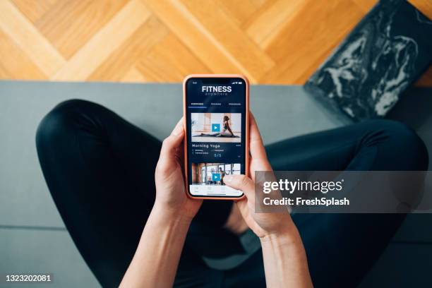 home workouts: anonymous woman following a yoga class on her mobile phone - fitness app stock pictures, royalty-free photos & images