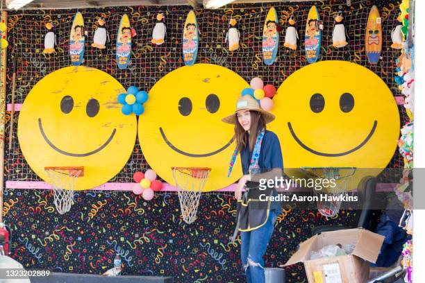 young woman carnival worker encouraging customers to play basketball game - midway utah stock pictures, royalty-free photos & images