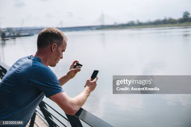 young man shops online on cellphone before morning run - sports clothing retail stock pictures, royalty-free photos & images