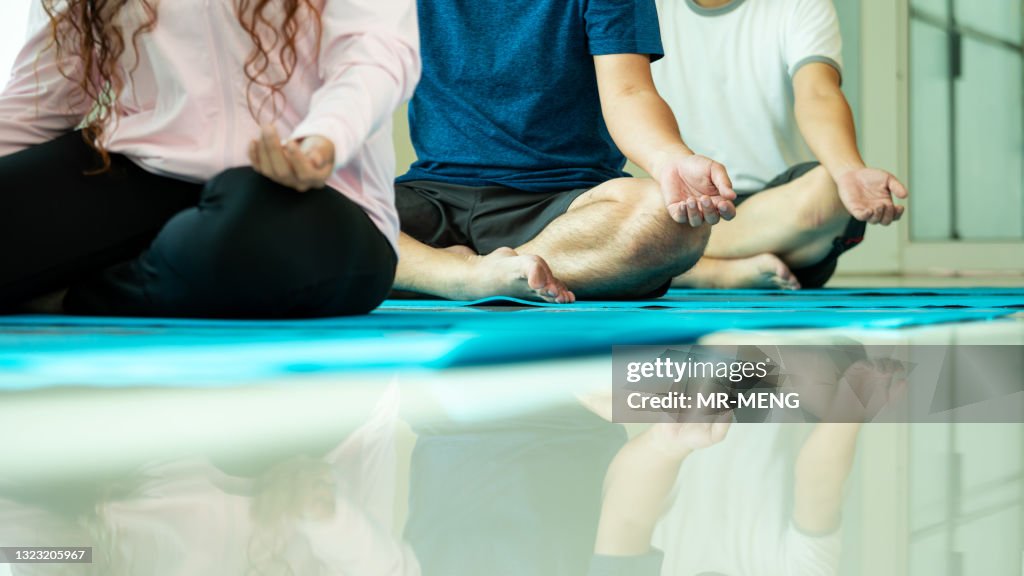Close up mudra hand of threee Asian men and woman sitting in row practices yoga breathing meditation