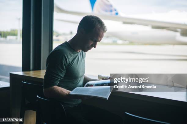 young man reads magazine and enjoys healthy meal in airport - glass magazine stock pictures, royalty-free photos & images