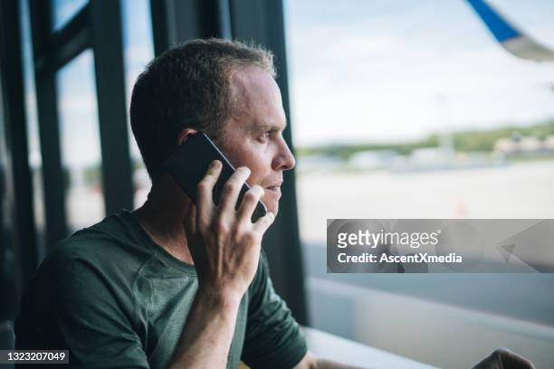 young man relaxes in departure area of airport - mobile on plane stock pictures, royalty-free photos & images