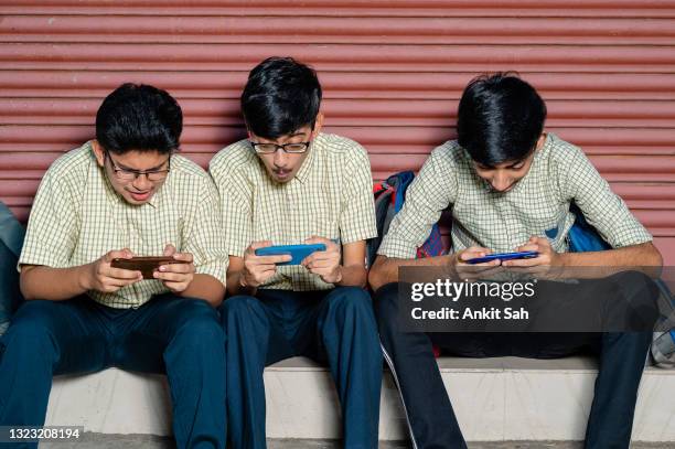 a group of three young students using smartphone in school campus. - mobile game stock pictures, royalty-free photos & images