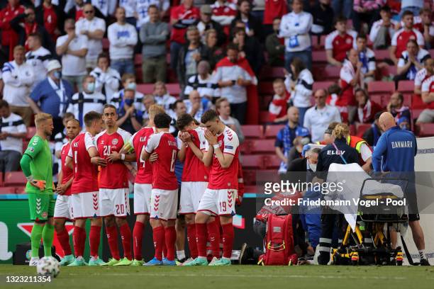 Players of Denmark stand dejected as Christian Eriksen of Denmark receives medical treatment during the UEFA Euro 2020 Championship Group B match...