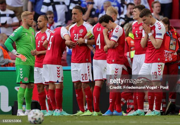 Kasper Schmeichel, Yussuf Poulsen, Thomas Delaney and Jonas Wind of Denmark look dejected as they surround Christian Eriksen of Denmark as he...