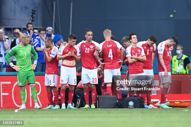 Joakim Maehle, Yussuf Poulsen, Simon Kjaer and Thomas Delaney of Denmark look dejected as team mate Christian Eriksen receives medical treatment...