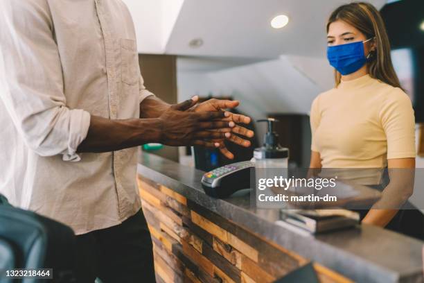 tourist cleaning hands with hand sanitizer in hotel - rubbing hands together stock pictures, royalty-free photos & images