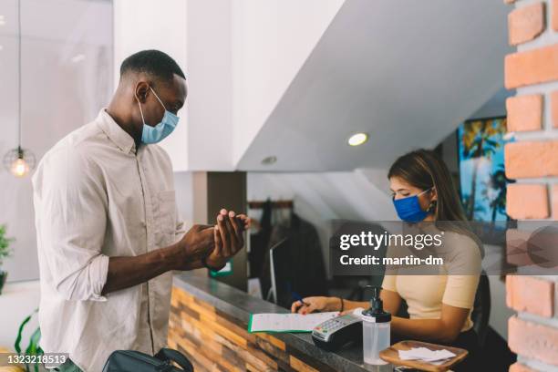 businessman disinfects hands at hotel reception, covid-19 pandemic - rubbing hands together stock pictures, royalty-free photos & images