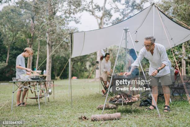 asian chinese senior man boiling stew soup for family camping dinner - asian family camping stock pictures, royalty-free photos & images