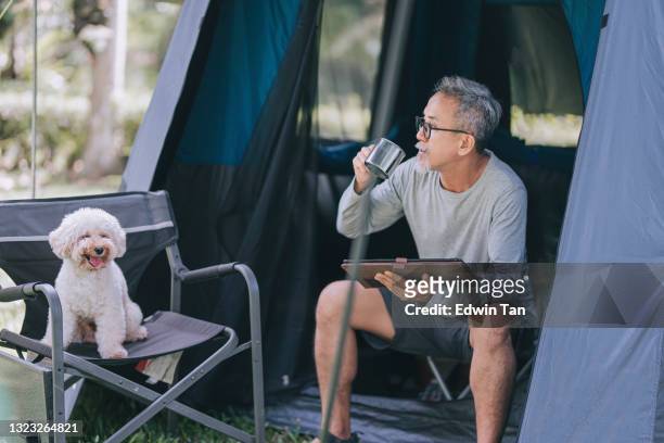 asian chinese senior man using digital tablet at camping chair in the morning with his toy poodle companion - coffee moustache stock pictures, royalty-free photos & images