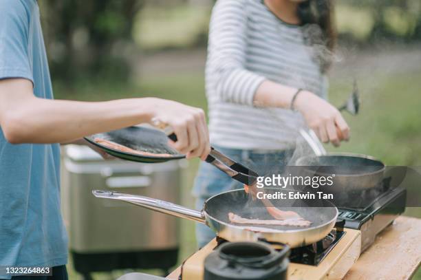 close up asian chinese teenage sibling preparing breakfast for family at camping - smokey bacon stock pictures, royalty-free photos & images