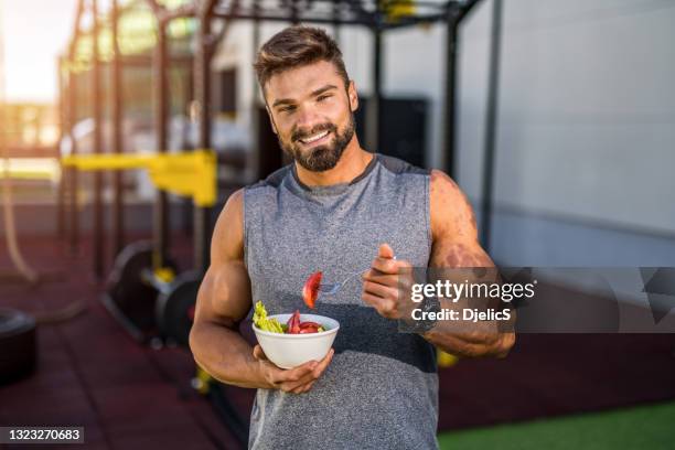 buon giovane bodybuilder che mangia un'insalata di verdure. - sportman foto e immagini stock