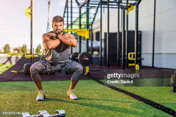 young bodybuilder doing squats workout at the outdoor gym. - bodyweight training stock pictures, royalty-free photos & images