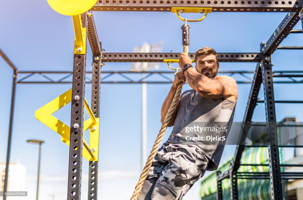 Bodybuilder In Ropes Young Bodybuilder Climbing The Rope At The Outdoor Gym High-Res Stock ...