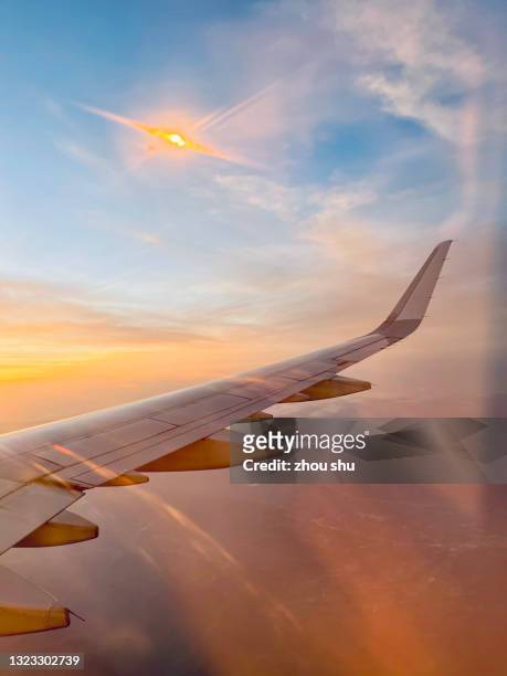 airplane wing flying in the sunset clouds - airplane wing stockfoto's en -beelden
