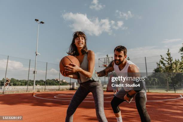 homem e mulher em meio agachamento jogando - bola de basquete - fotografias e filmes do acervo