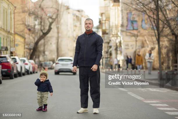 stylish young man and his cute daughter on the street - alta moda fotografías e imágenes de stock