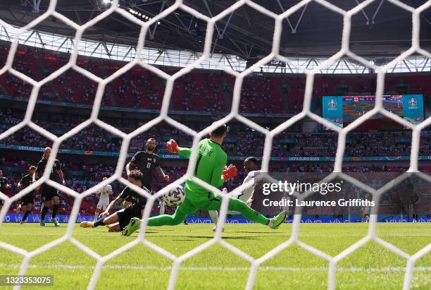 Raheem Sterling of England scores their side's first goal past Dominik Livakovic of Croatia whilst under pressure from Sime Vrsaljko of Croatia...