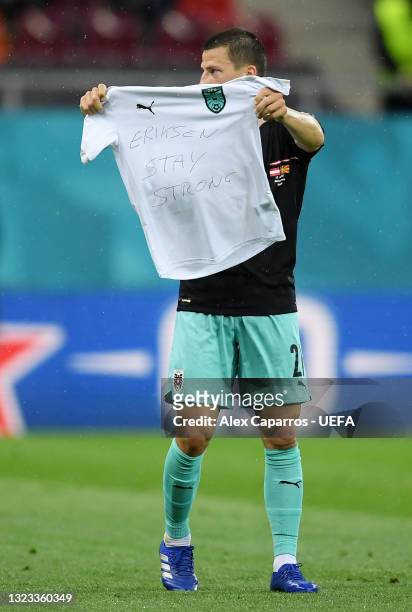 Stefan Lainer of Austria celebrates after scoring their side's first goal whilst holding a t-shirt with a message of support for Christian Eriksen of...