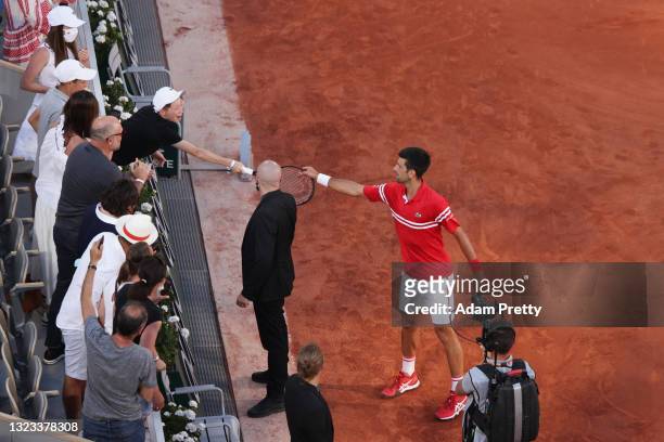 Tournament winner Novak Djokovic of Serbia passes his racquet to a fan as he celebrates after winning his Men's Singles Final match against Stefanos...
