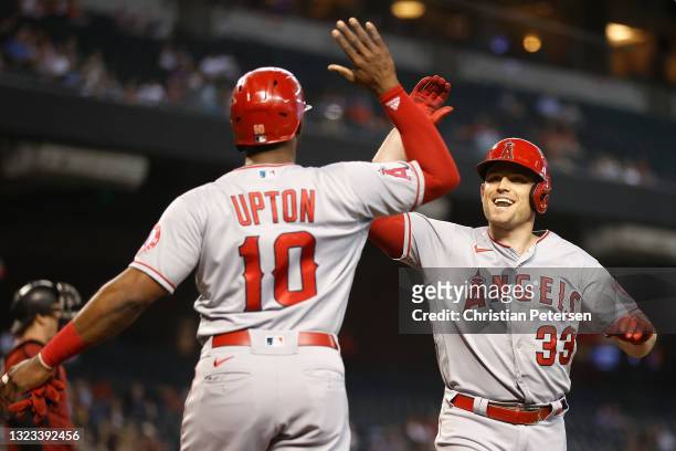 Max Stassi of the Los Angeles Angels high fives Justin Upton after hitting a two-run home run against the Arizona Diamondbacks during the first...