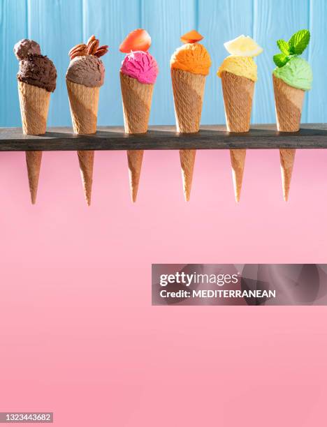 assorted ice cream waffle cones in a row colorful different flavor on pink and blue wood - mint chocolate chip ice cream scoop stock pictures, royalty-free photos & images