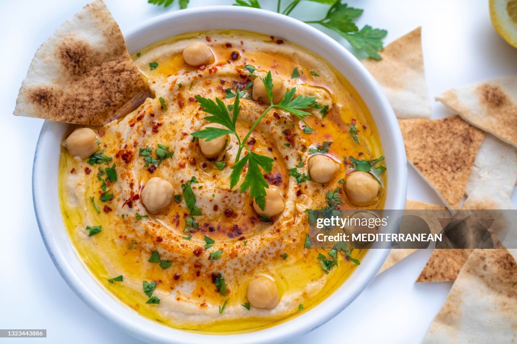 Chickpea hummus bowl closeup with pita flatbread dipping isolated on white