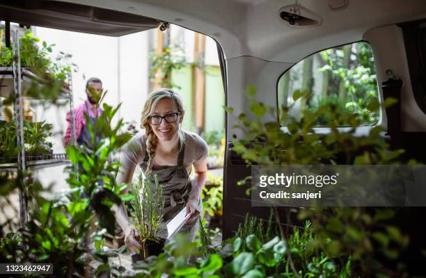 gartencenter-mitarbeiter transportieren pflanzen - gärtnerei stock-fotos und bilder