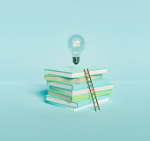 Stack of books with light bulb and ladder