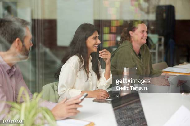 a startup business meeting around a conference table. - gefotografeerd door het raam stockfoto's en -beelden