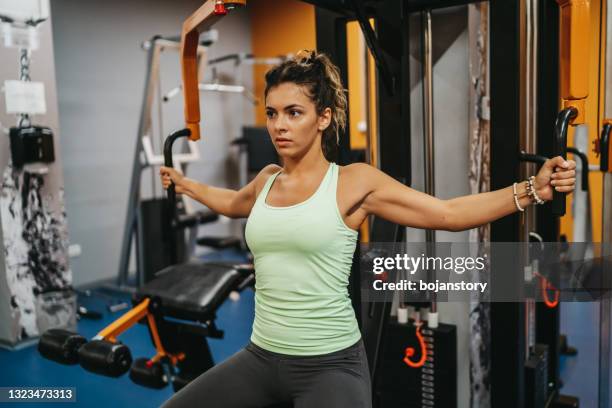 beautiful young woman exercising in a fitness center - pectoral muscle stock pictures, royalty-free photos & images