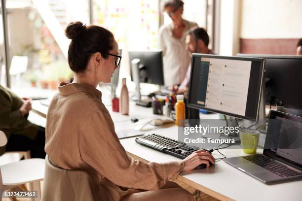 a businesswoman sending e-mails in an office. - versturen stockfoto's en -beelden