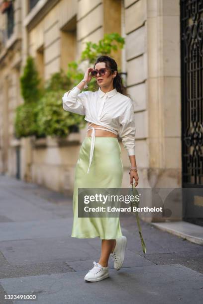 Ketevan Giorgadze @katie.one wears oversized square sunglasses in mauve by For Art’s Sake, a pistachio green flowy lustrous satin midi skirt by...