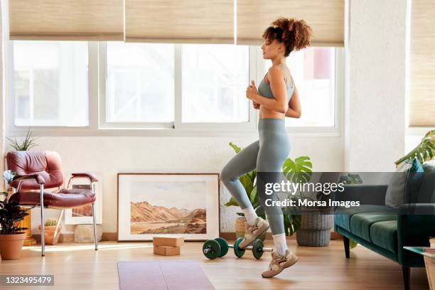 young woman practicing exercise at home - morsa images stock pictures, royalty-free photos & images