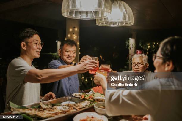 cheers! thai family clink while having dinner party-stock photo - family reunion stock pictures, royalty-free photos & images