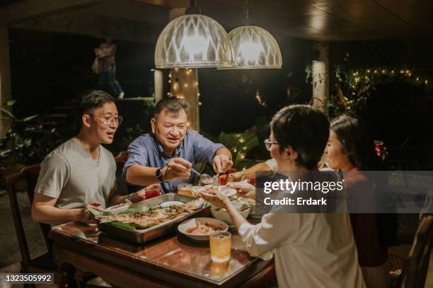 papà tailandese che dà del cibo alla moglie accanto alla foto di famiglia - cultura orientale foto e immagini stock