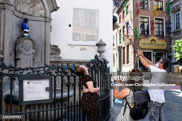 People take photos of the Manneken-pis, symbol of the city of Brussels, dressed in the NATO colors for the international summit on June 14, 2021 in...